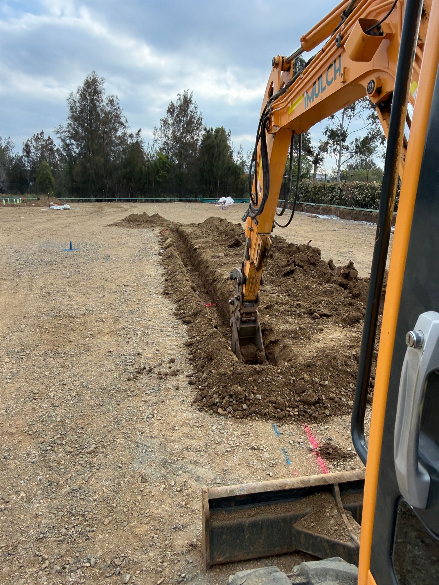 Excavator digging a drainage trench on a commercial construction site